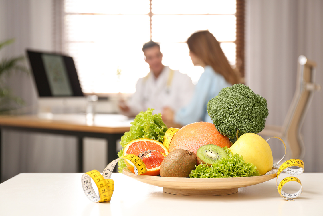 Nutritionist Consulting Patient at Table in Clinic, Focus on Pla